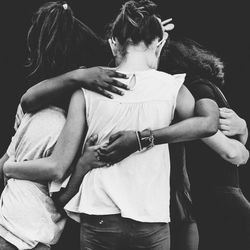 Friends huddling while standing outdoors