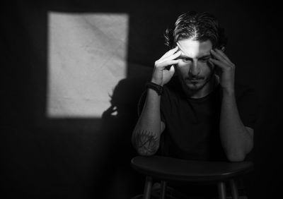 Worried man sitting with head in hands on seat at home