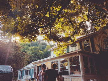 Rear view of friends standing against house