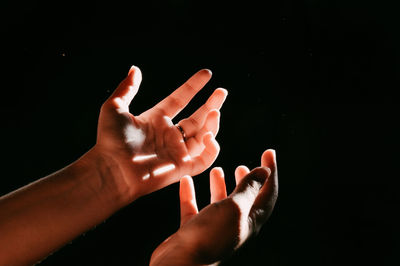 Cropped hands gesturing against black background