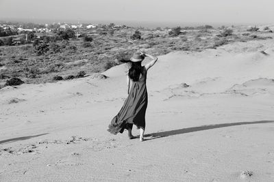 Woman walking on beach against sky