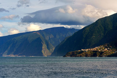 Scenic view of sea by mountains against sky