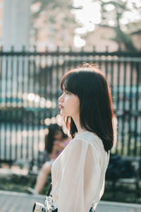 Side view of young woman looking away outdoors