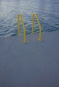 High angle view of yellow metallic railing over sea