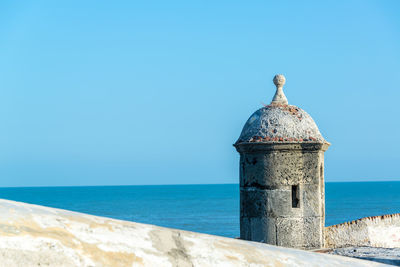 Castle by sea against clear blue sky on sunny day