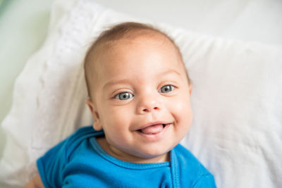 Directly above portrait of baby boy smiling while lying in crib