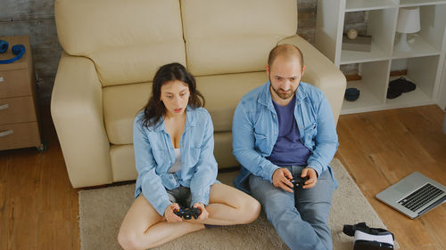 Full length of friends sitting on sofa at home