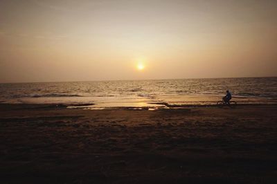 Silhouette of man on beach against sky during sunset