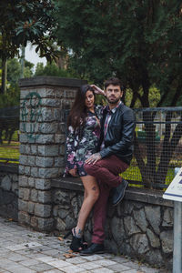 Full length of couple kissing while standing against trees