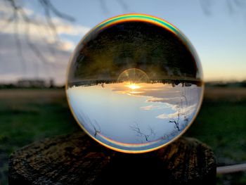 Close-up of crystal ball on glass against sunset