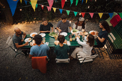 High angle view of multi-ethnic friends having food at table during dinner party in backyard