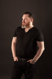 Portrait of young man standing against black background