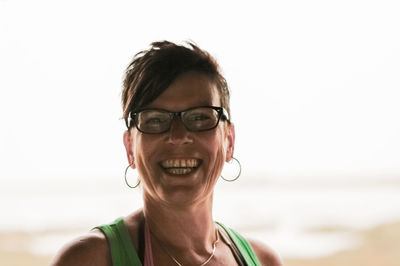 Portrait of smiling woman wearing sunglasses against sky