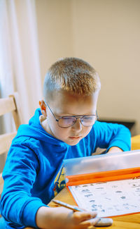 Side view of boy looking away while sitting at home