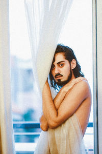 Portrait of young man looking through window