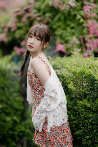 Young woman standing against plants