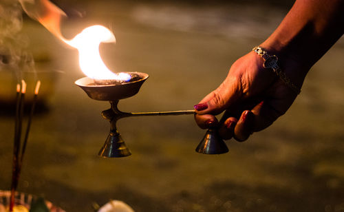 Close-up of hand holding lit candles in temple