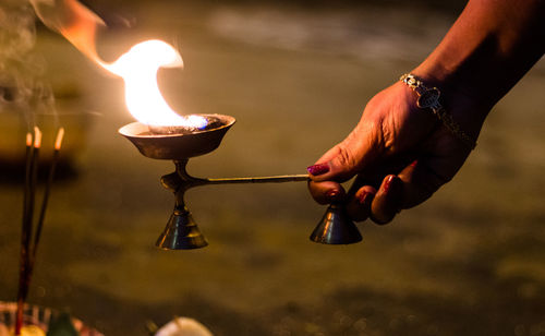 Close-up of hand holding lit diya in temple