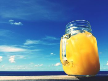 Close-up of yellow jar on sea against blue sky