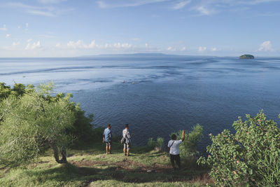 Rear view of people on sea shore against sky