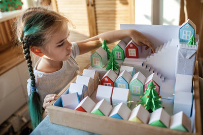 Origami advent calendar, paper craft. girl looking upon paper houses with number and paper tree