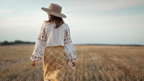 Rear view of woman standing on field against sky