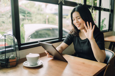 Young woman using phone while sitting on table