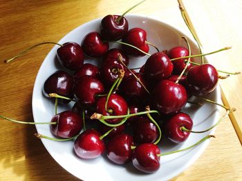 High angle view of red cherry fruits in bowl on table