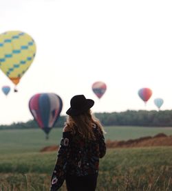 Rear view of woman looking at balloons against sky