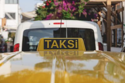 Bright yellow taxi sign on the roof of a yellow car on a sunny day.