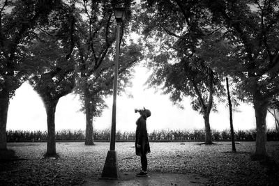 Man standing by tree on field against sky