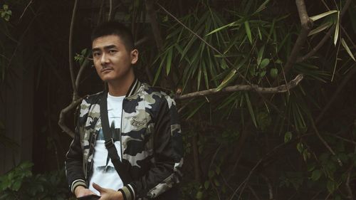 Portrait of young man standing in forest at night