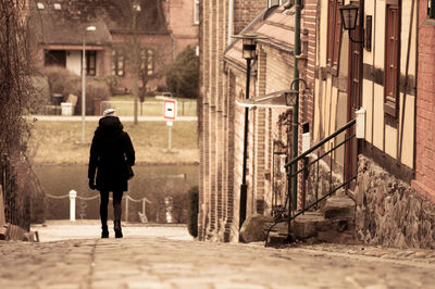 Full length of woman walking on pathway by building in town