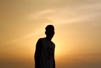 Silhouette man standing against orange sky