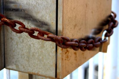 Close-up of metallic box locked with rusty chain