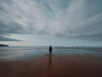 Rear view of silhouette man walking on beach