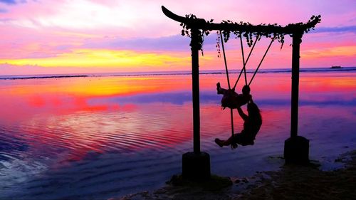 Silhouette man by sea against sky during sunset