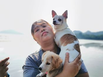 Dog and woman with dogs on water against clear sky