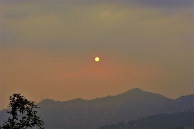 Scenic view of silhouette mountains against orange sky