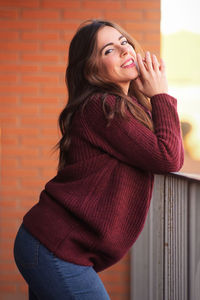 Portrait of a smiling young woman standing against wall