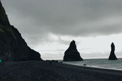 Silhouette rocks on beach against sky