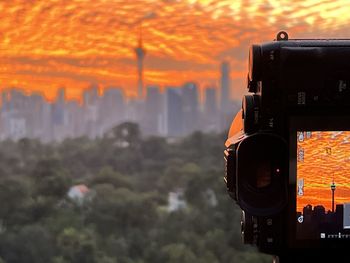 Close-up of camera against sky during sunset