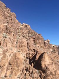 Low angle view of rocky mountains against blue sky