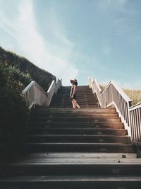Low angle view of woman standing on staircase against sky