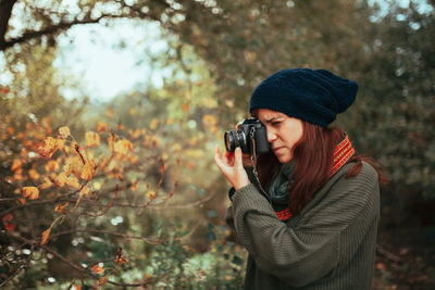 Young woman taking photos in the forest with an old analog camera