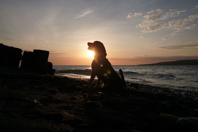 Silhouette rocks on beach against sky during sunset