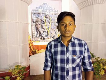 Portrait of young man standing against wall