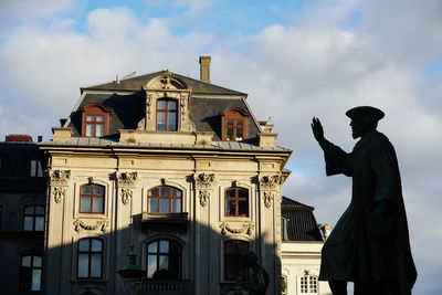 Low angle view of building and statue against sky