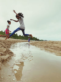 Rear view of people enjoying at beach against sky