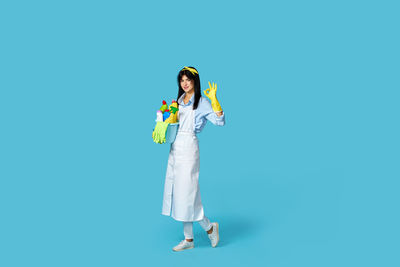 Portrait of young woman standing against blue background